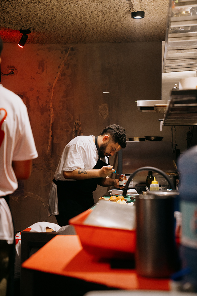 Chef de Tresca preparando platos con dedicación durante el servicio nocturno.