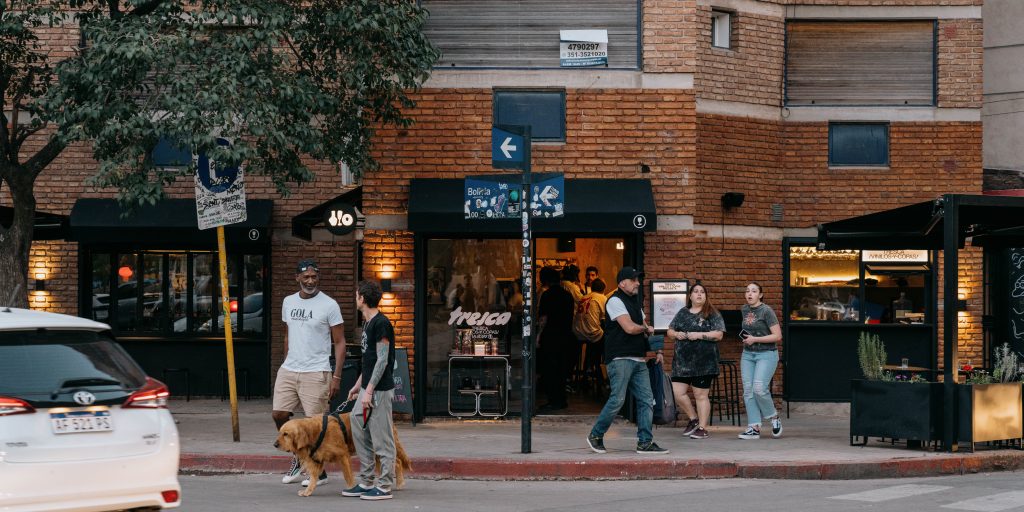 Fachada de Tresca bar de vinos y vinilos al atardecer, frente al Parque Las Tejas, con movimiento urbano y público en la vereda.